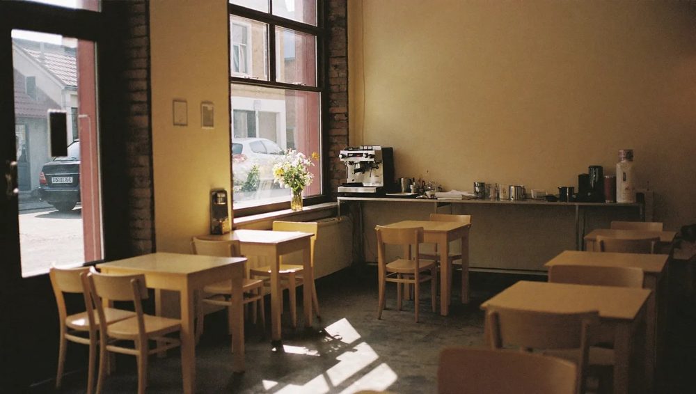 The room at Fika Cafe: wooden tables and chairs by a wide front window